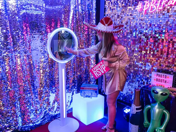 Young woman touching screen of Cloee photo booth during company event in DFW